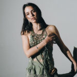 Lucy Vives promotes her acoustic single "Nido" with artistic floral visuals.