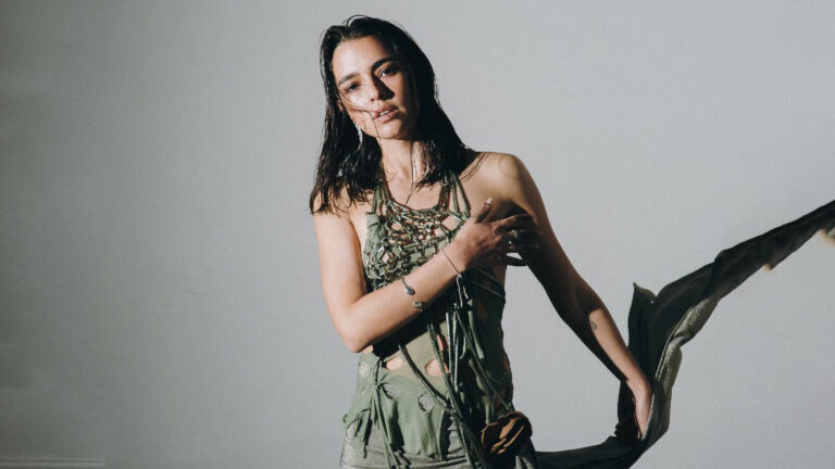 Lucy Vives promotes her acoustic single "Nido" with artistic floral visuals.